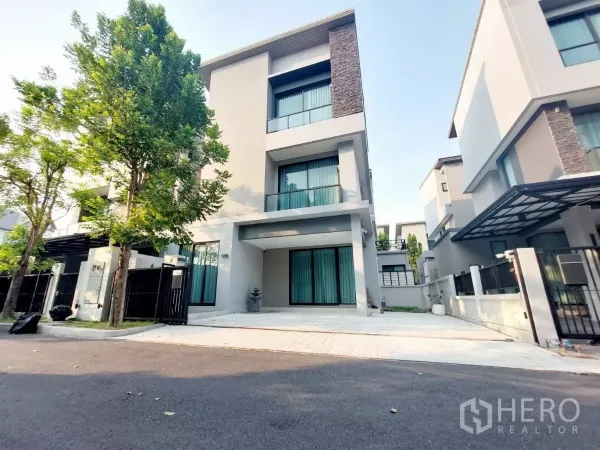 联排别墅 出租在Lat Phrao, Bangkok - 拉抛区现代三层联排别墅外观，带大门与车道，街道绿树成荫。