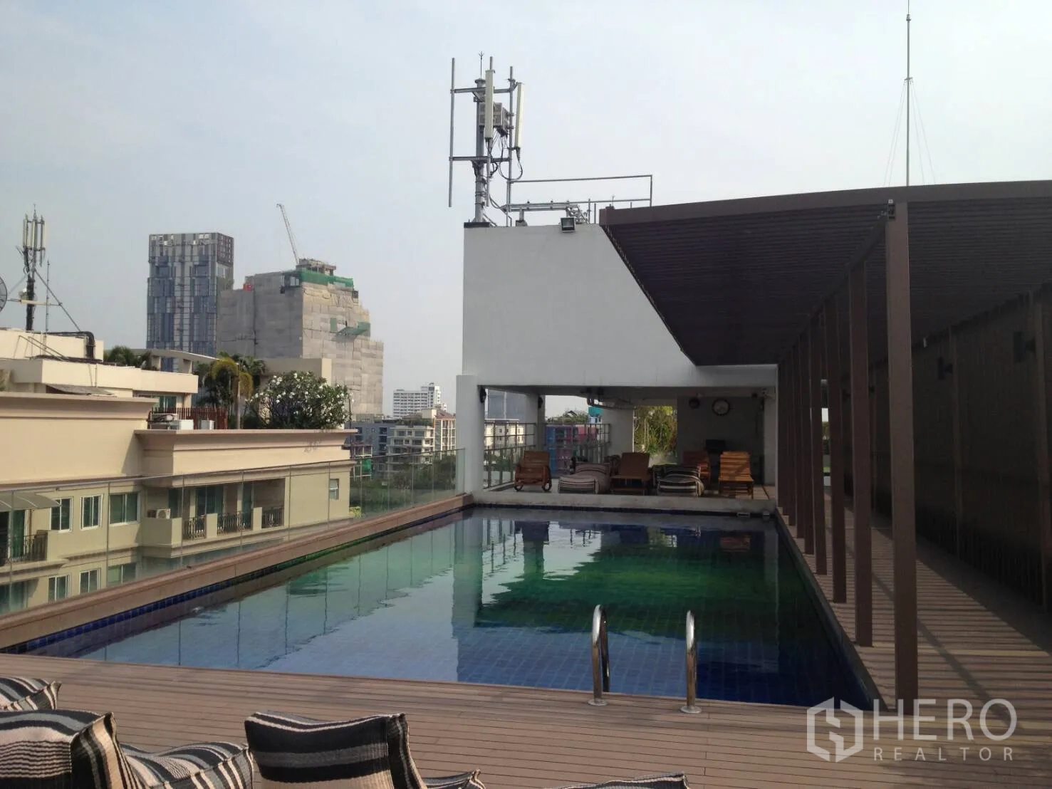 Condominium for rent in Khlong Toei, Bangkok - Rooftop swimming pool with sun deck and pergola overlooking the Bangkok skyline.