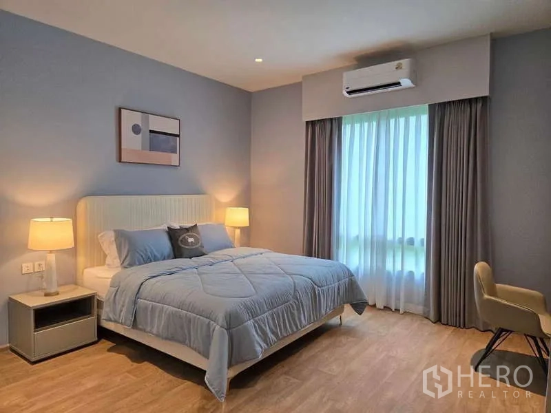 Detached House for rent or sale in Lat Krabang, Bangkok - Bright bedroom with soft blue walls, queen bed, and draped window.
