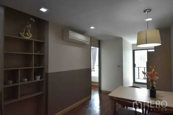Condominium for rent in Khlong Toei, Bangkok - Open-plan dining area with built-in shelving, air conditioning, and access to a bright bedroom.