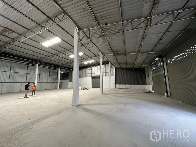 货栈 出租在Khlong Luang, Pathum Thani - 仓库内朝向多扇卷闸门与通风砖墙，适合仓储或作业。