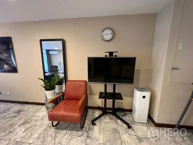 Townhouse for rent or sale in Suan Luang, Bangkok - Decor nook featuring a quilted leather chair, full-length mirror, TV on stand and air purifier.
