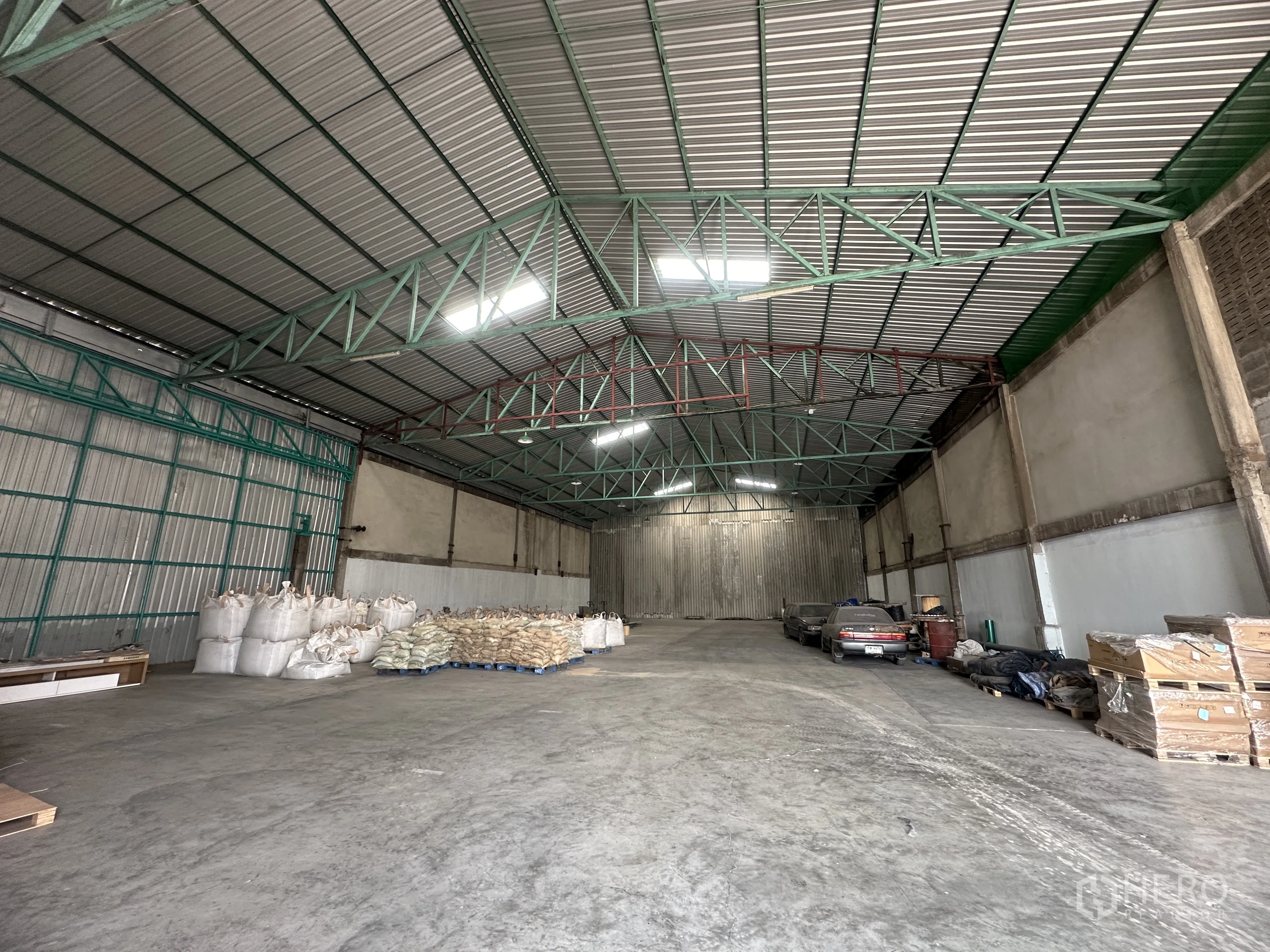 Warehouse for rent in Mueang Pathum Thani, Pathum Thani - Spacious warehouse interior with high steel truss roof, skylights and smooth concrete floor.