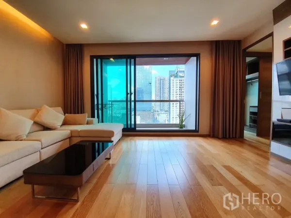 Condominium for rent in Bang Rak, Bangkok - Living room opening to a glass-railed balcony overlooking the Bangkok skyline.