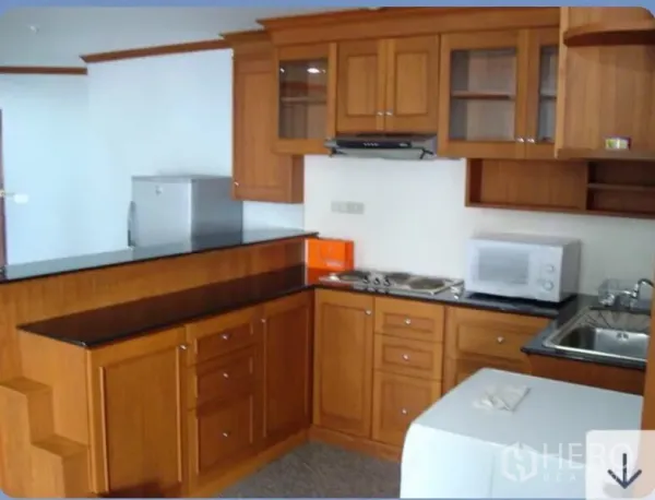 Condominium for rent in Ratchathewi, Bangkok - U-shaped kitchen with wooden cabinets, black countertops, cooktop and sink
