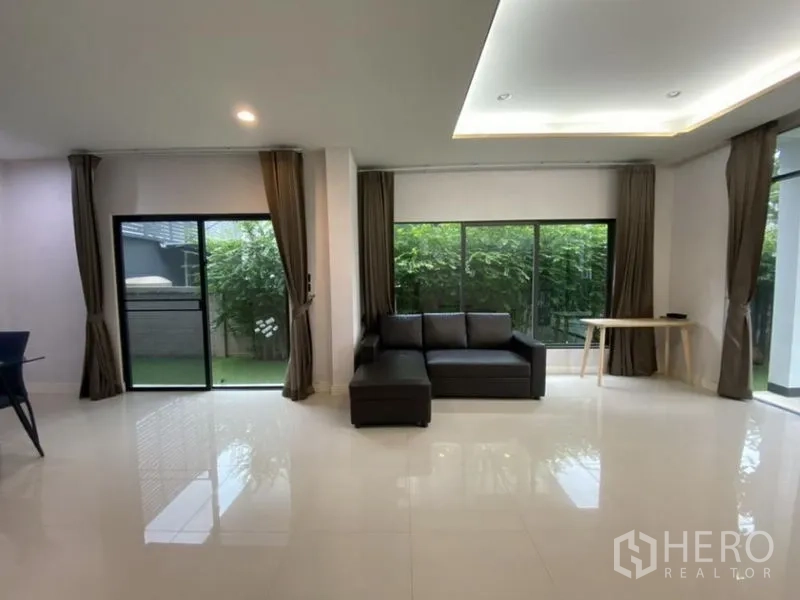 บ้าน ให้เช่าในBang Kapi, Bangkok - โซฟาเข้ามุมติดหน้าต่างเต็มบาน เชื่อมต่อสวนด้วยประตูกระจก