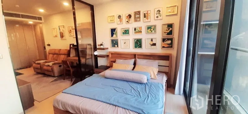 Condominium for rent or sale in Huai Khwang, Bangkok - Bright bedroom with queen bed, wall art, and floor-to-ceiling window.