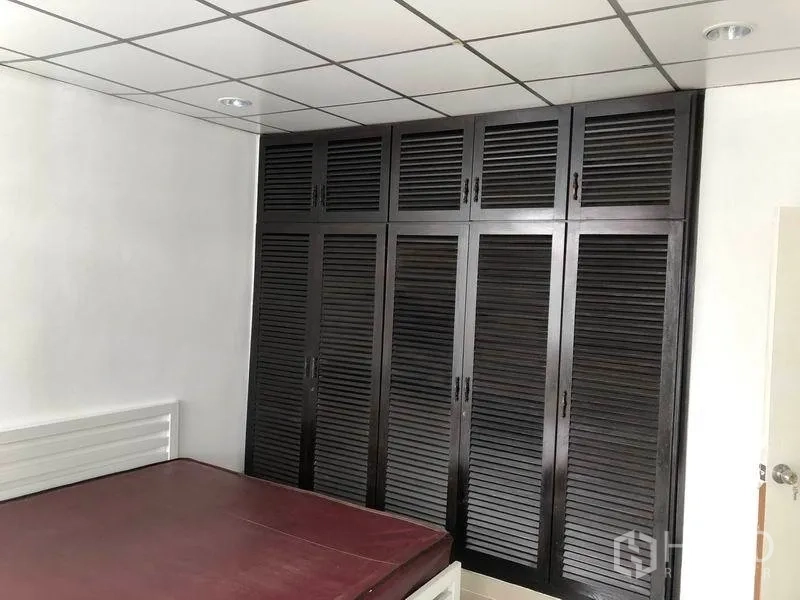 Townhouse for rent in Watthana, Bangkok - Bedroom featuring a full wall of dark louvered built-in wardrobes.