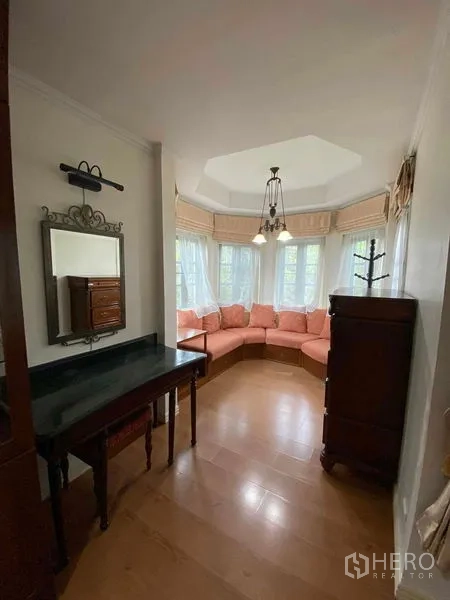 Townhouse for rent or sale in Mueang Samut Prakan, Samut Prakan - Bay-window alcove with pink sectional sofa and chandelier.