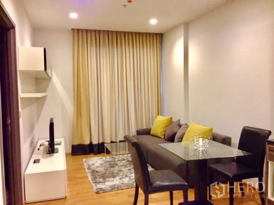 公寓 出租在Khlong Toei, Bangkok - 客厅配灰色沙发、玻璃茶几、电视柜与落地窗帘