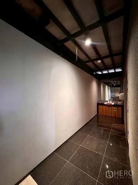 Warehouse for rent in Prawet, Bangkok - Hallway with glossy floor tiles leading to washroom and service area.