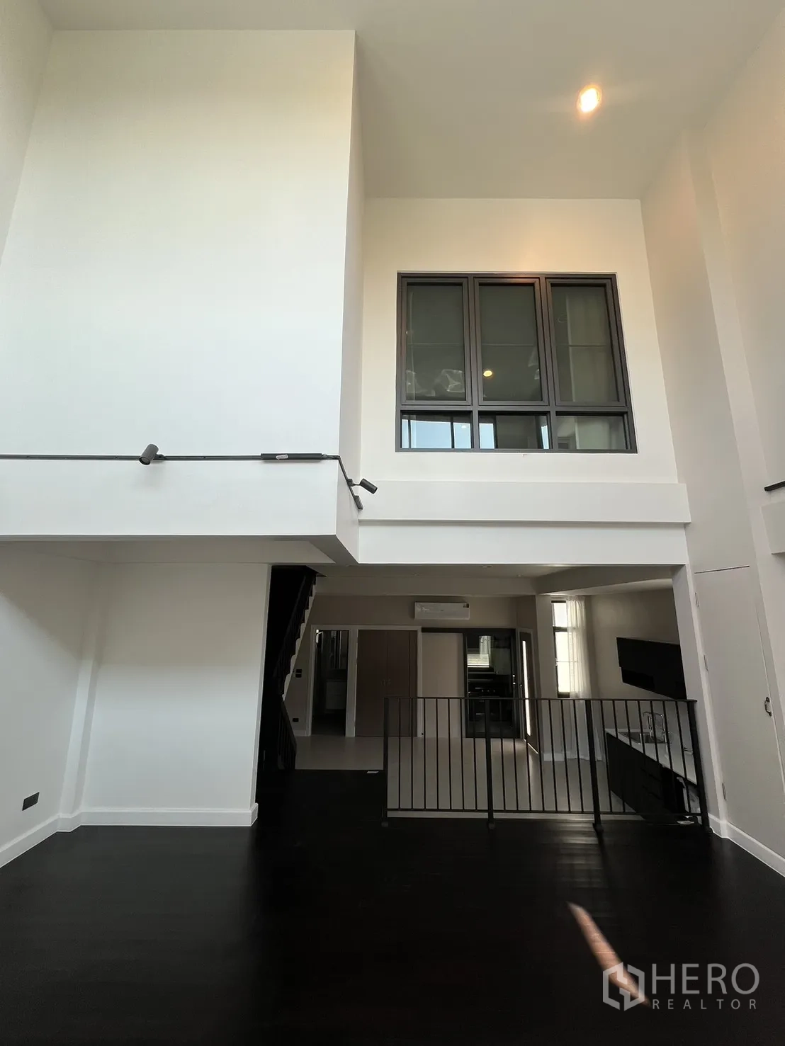 Detached House for rent in Saphan Sung, Bangkok - Double-height mezzanine lounge with dark wood flooring and interior windows.
