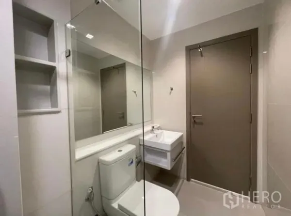 公寓 出租在Ratchathewi, Bangkok - 明亮卫生间，超大镜面、坐便器与悬空洗手台。