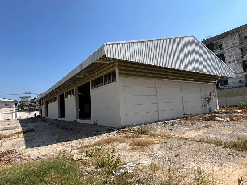 Warehouse for rent or sale - Exterior corner view of a single-storey warehouse with metal roof and cream walls.