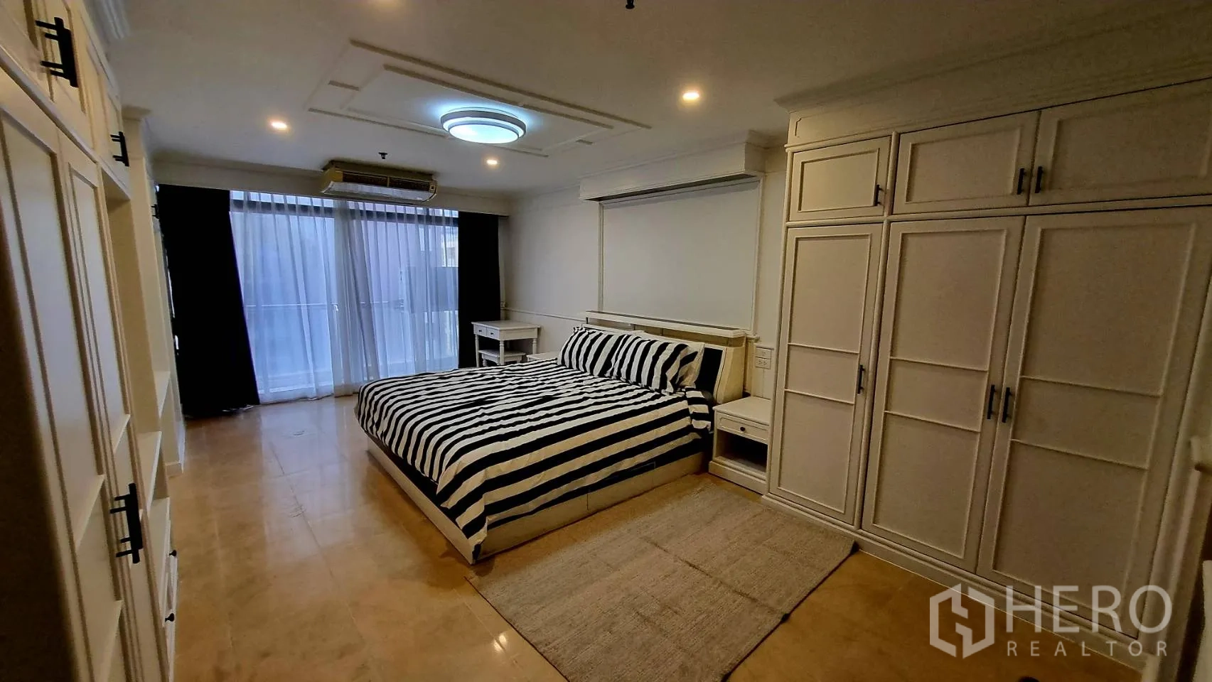 Condominium for rent in Watthana, Bangkok - Master bedroom facing balcony with built-in storage.