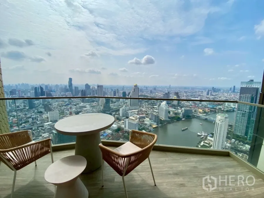 公寓 出租在Khlong San, Bangkok - 私人阳台配圆桌与两把椅子，俯瞰湄南河与曼谷天际线。