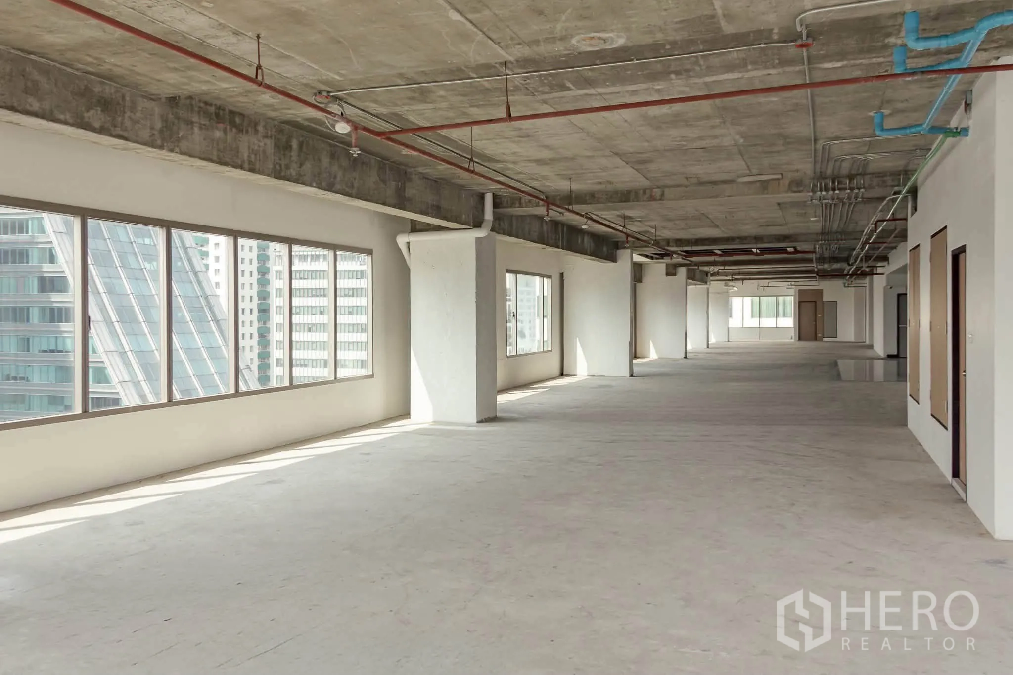 办公室 for rent in Watthana, Bangkok - 宽敞毛坯办公楼层，宽大窗户带城市天际线景观，裸露混凝土天花与可见管线。