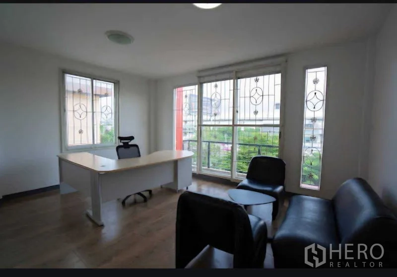 Home Office for rent or sale in Lat Krabang, Bangkok - Corner executive office with sofa seating and large windows with security grilles.