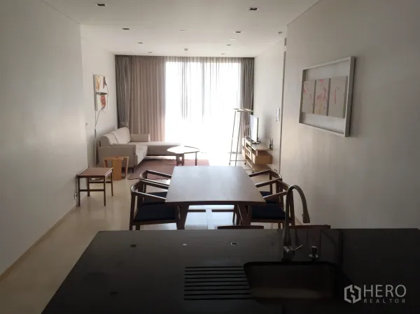 公寓 出租在Bang Rak, Bangkok - 开放式客餐厅与厨房岛台，配沙发、电视柜与落地纱帘采光。