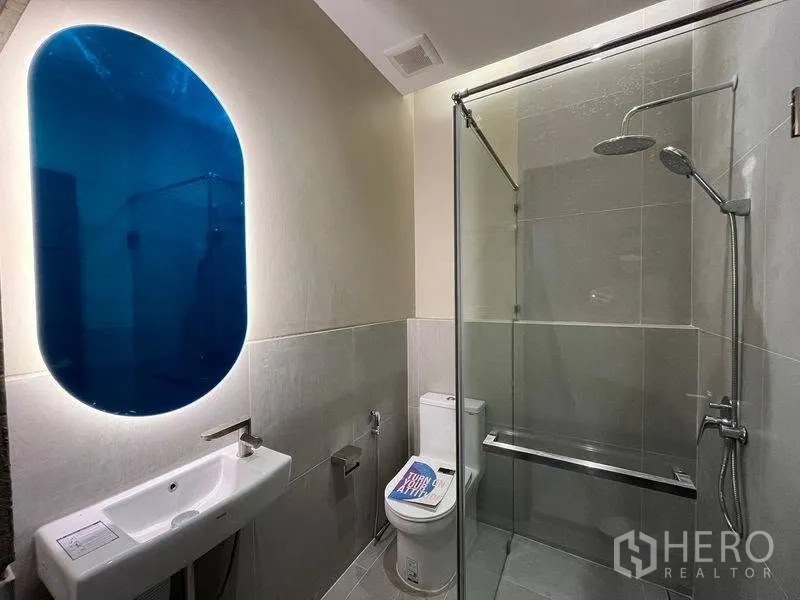 ทาวน์เฮาส์ for rent in Phra Khanong, Bangkok - ห้องน้ำสไตล์โมเดิร์น กระจกเงาสีน้ำเงินมีไฟ ตู้อาบน้ำกระจกและโถสุขภัณฑ์.