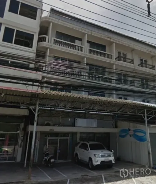 Home Office for rent in Bang Phli, Samut Prakan - Four-storey home office facade with glass entry, balconies and covered front parking along a main road in Bang Phli.