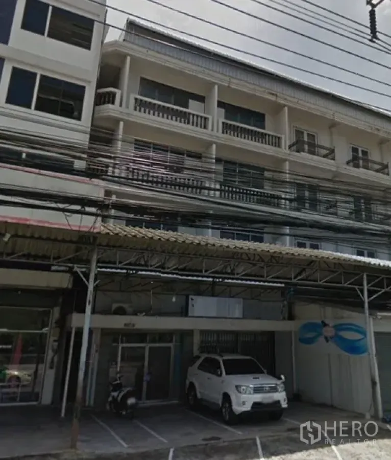 Home Office for rent in Bang Phli, Samut Prakan - Four-storey home office facade with glass entry, balconies and covered front parking along a main road in Bang Phli.