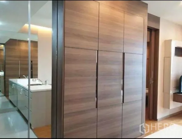 公寓 出租在Bang Rak, Bangkok - 走廊设大型木质嵌入式衣柜与镜面盥洗台，通往浴室。