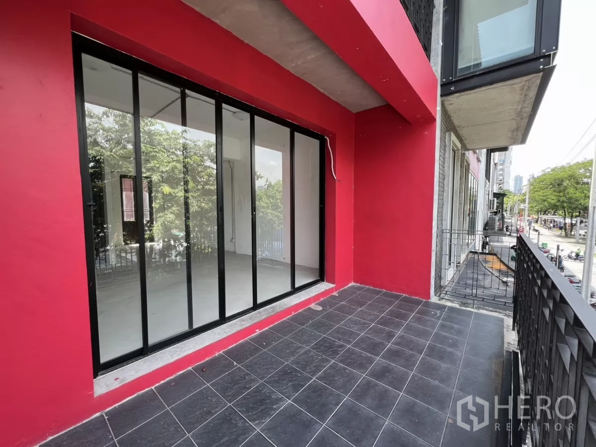 Retail Space for rent in Khlong Toei, Bangkok - Second-floor terrace with black tiles and a full glass storefront overlooking trees and the street.