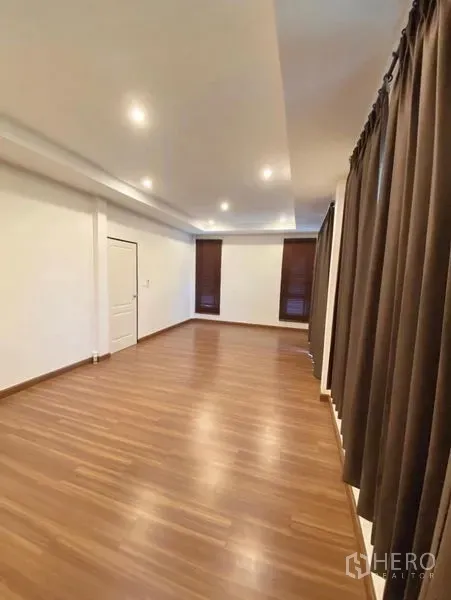 Detached House for sale in Bang Phli, Samut Prakan - Large bedroom with wood floors, recessed lighting, and full-length blackout curtains.