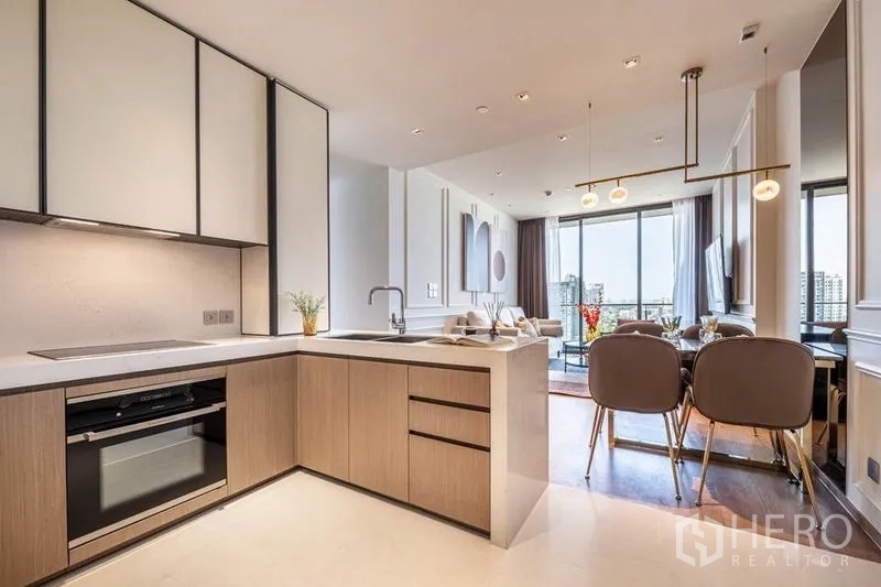Condominium for rent in Khlong Toei, Bangkok - Stylish kitchen and dining area leading to a bright living room with views.