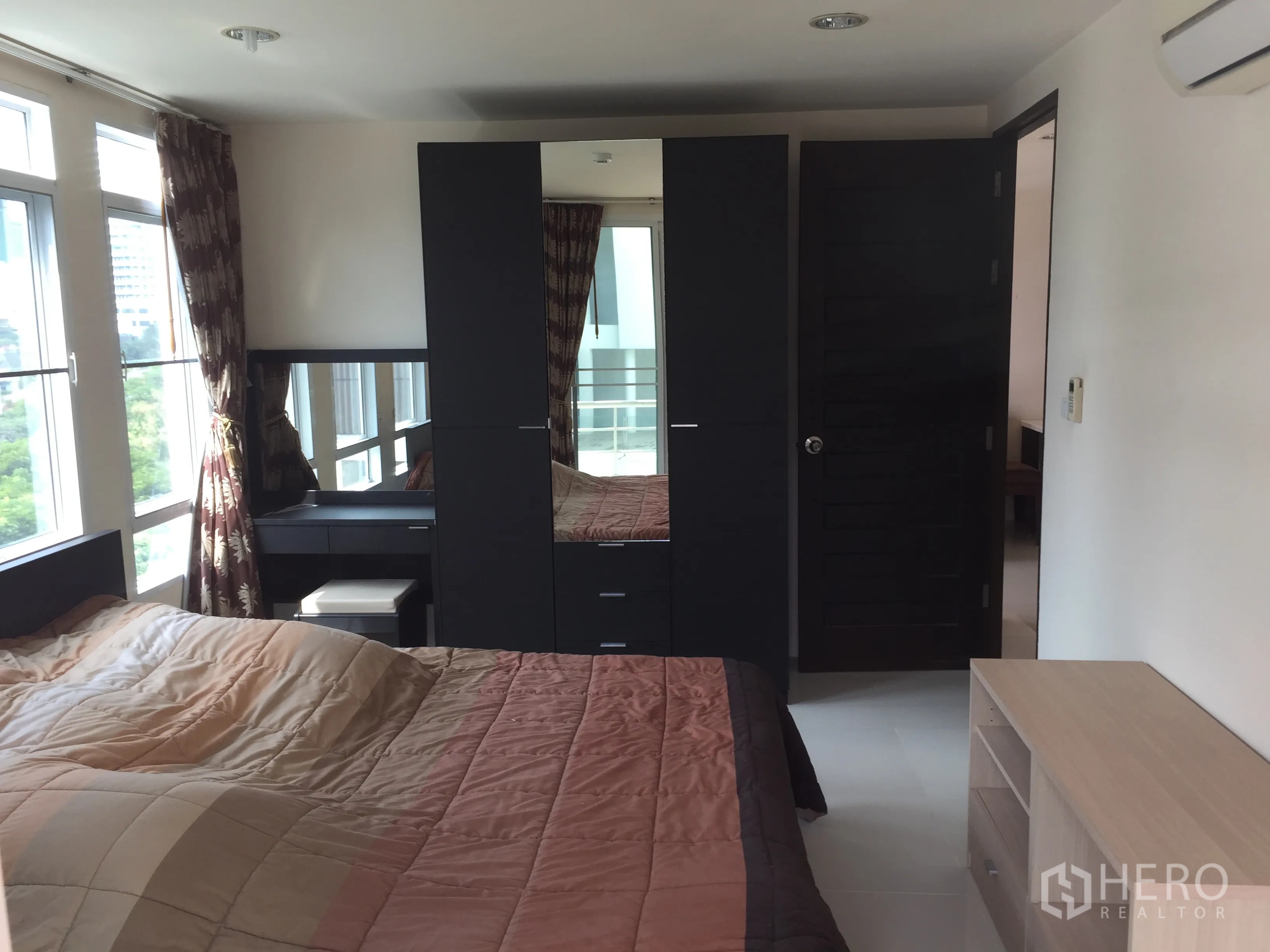 公寓 出租或出售在Watthana, Bangkok - 卧室配深色衣柜、梳妆台与大转角窗。