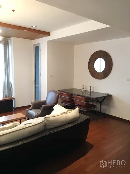 Condominium for rent or sale in Khlong Toei, Bangkok - Dining corner featuring a glass-top table, round mirror and seating beside the living area.