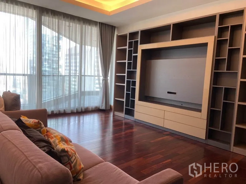 Condominium for rent in Sathon, Bangkok - Cozy lounge corner with full‑height curtains, hardwood floors, and built‑in shelving for a TV.