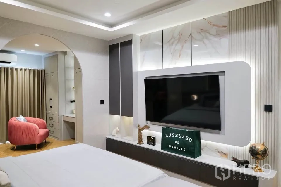 บ้านเดี่ยว for sale in Bang Phli, Samut Prakan - ห้องนอนหลักพร้อมผนังทีวีและซุ้มโค้งเชื่อมสู่มุมนั่งเล่น.