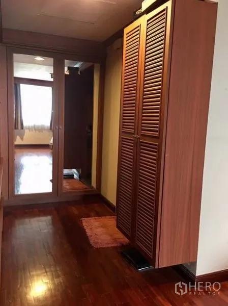 Condominium for rent or sale in Watthana, Bangkok - Hallway with wooden wardrobes, louvered doors and a mirrored closet.
