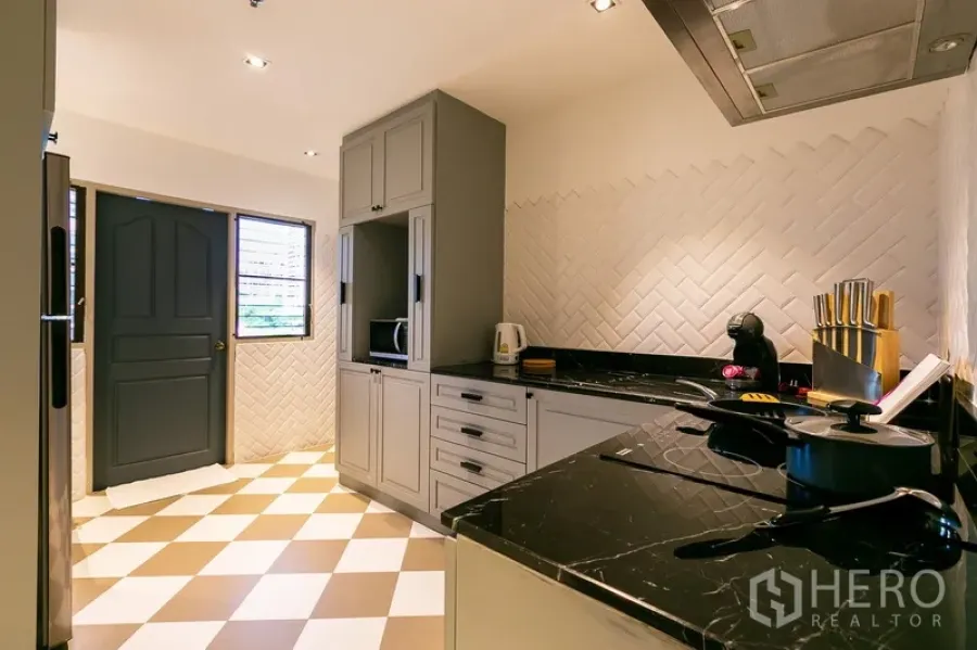 Apartment for rent in Khlong Toei, Bangkok - Closed kitchen perspective with window, appliances and herringbone tile backsplash.