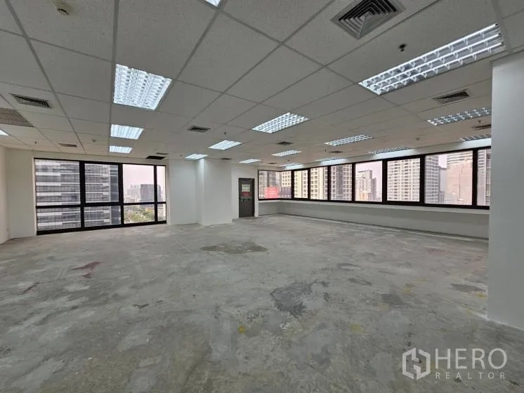 Office Space for rent in Bang Rak, Bangkok - Large open-plan office with drop ceiling lights and corner windows overlooking Bangkok skyline.