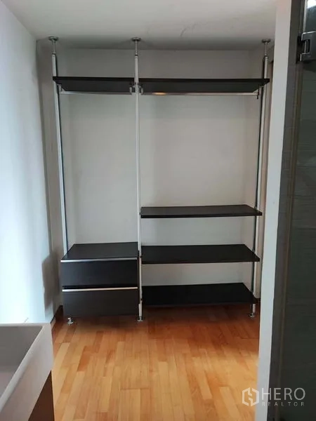 Condominium for sale in Khlong Toei, Bangkok - Walk-in closet area with black open shelves, drawers and hanging rails.