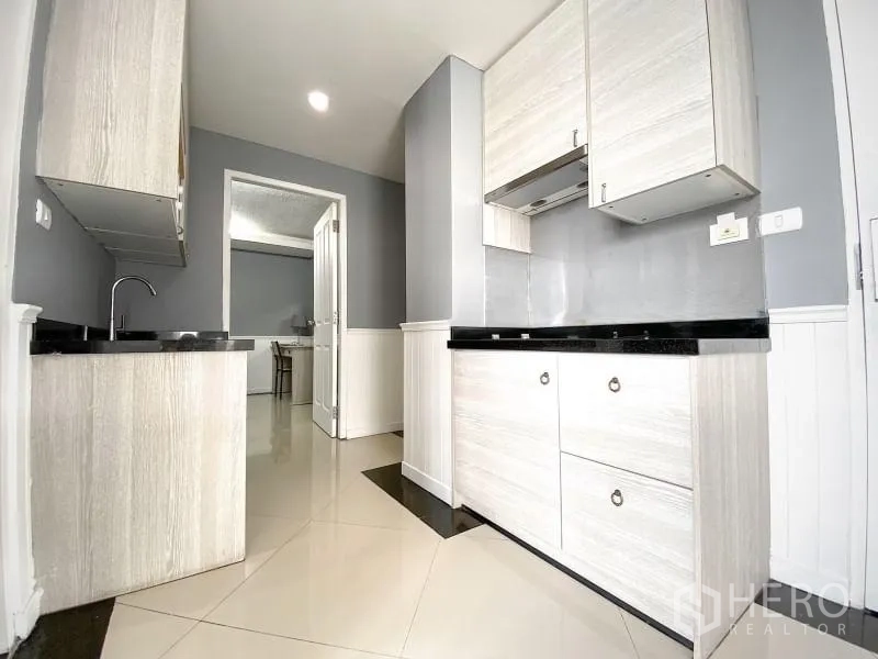 Condominium for rent in Khlong Toei, Bangkok - Kitchen view with additional cabinets, extractor and ample counter space.
