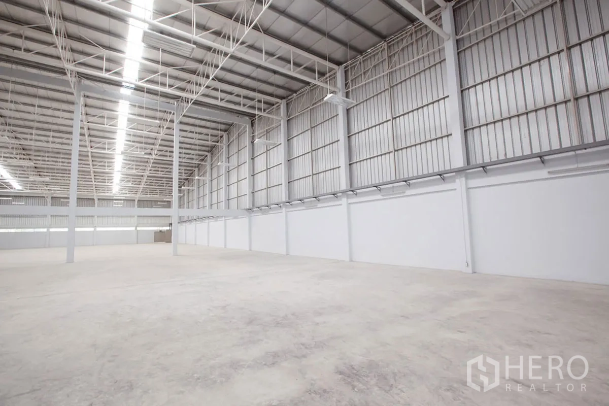 Factory for rent in Si Racha, Chon Buri - Wide-span warehouse hall with steel trusses, ventilated walls, and concrete floor.