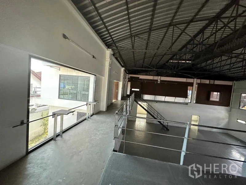 คลังสินค้า ให้เช่าในPhra Khanong, Bangkok - ชานพักชั้นลอยมองเห็นพื้นที่โกดังเพดานสูงและหน้าต่างบานใหญ่พร้อมโครงหลังคาเหล็ก