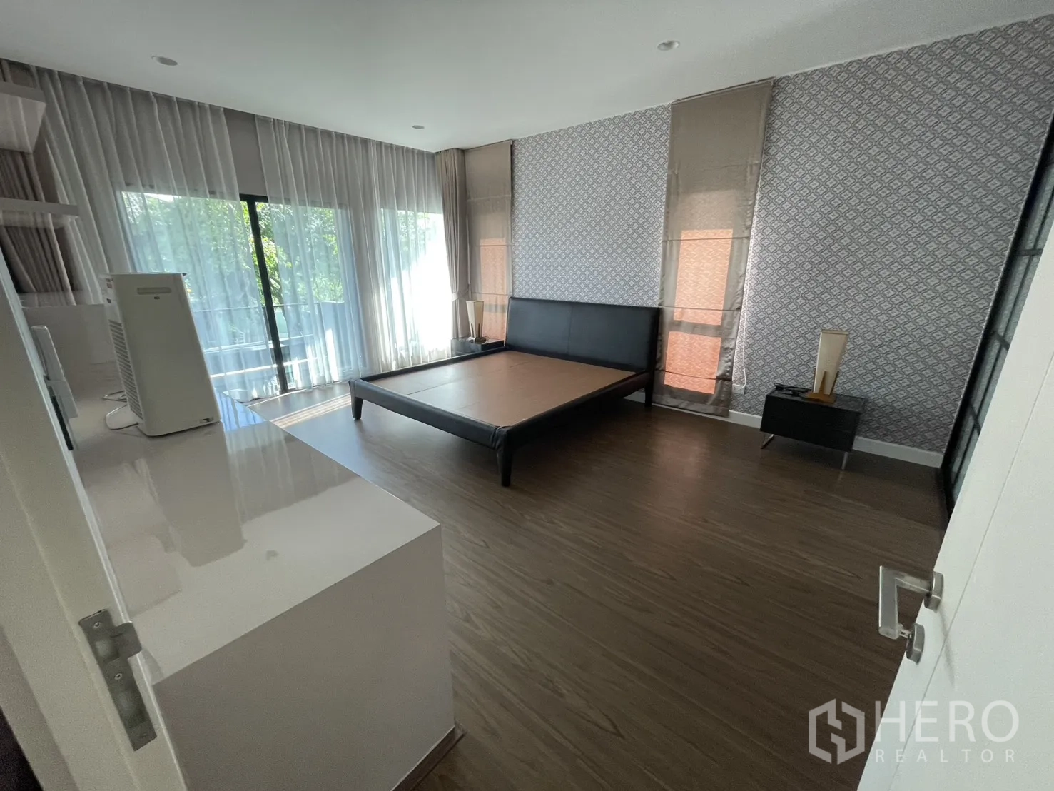 Detached House for rent or sale in Lam Luk Ka, Pathum Thani - Large master bedroom with balcony access, patterned feature wall and ample space.