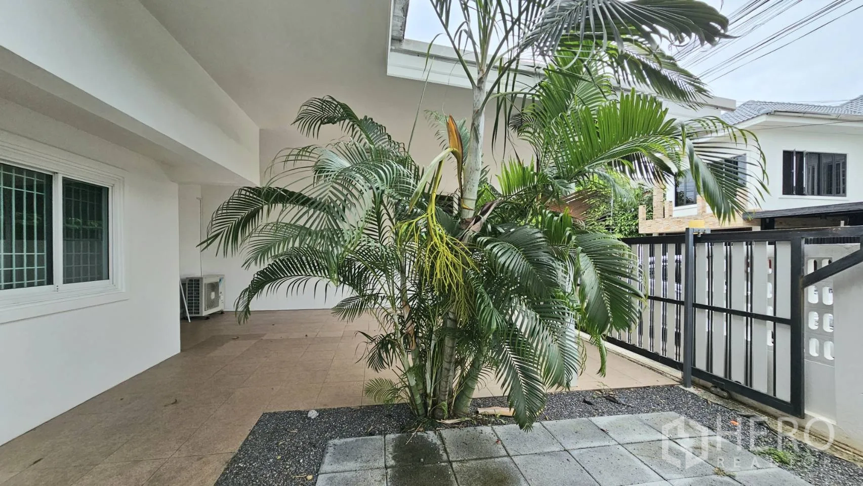 独栋房屋 for rent in Saphan Sung, Bangkok - 覆顶前庭，热带植物旁的滑动栅栏门与地砖。