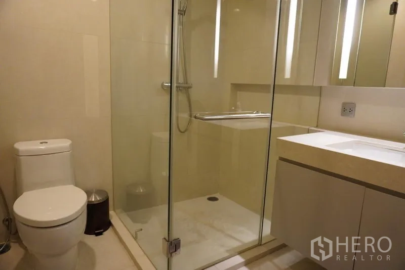 Condominium for rent in Watthana, Bangkok - Contemporary bathroom with glass-enclosed shower, vanity and toilet.