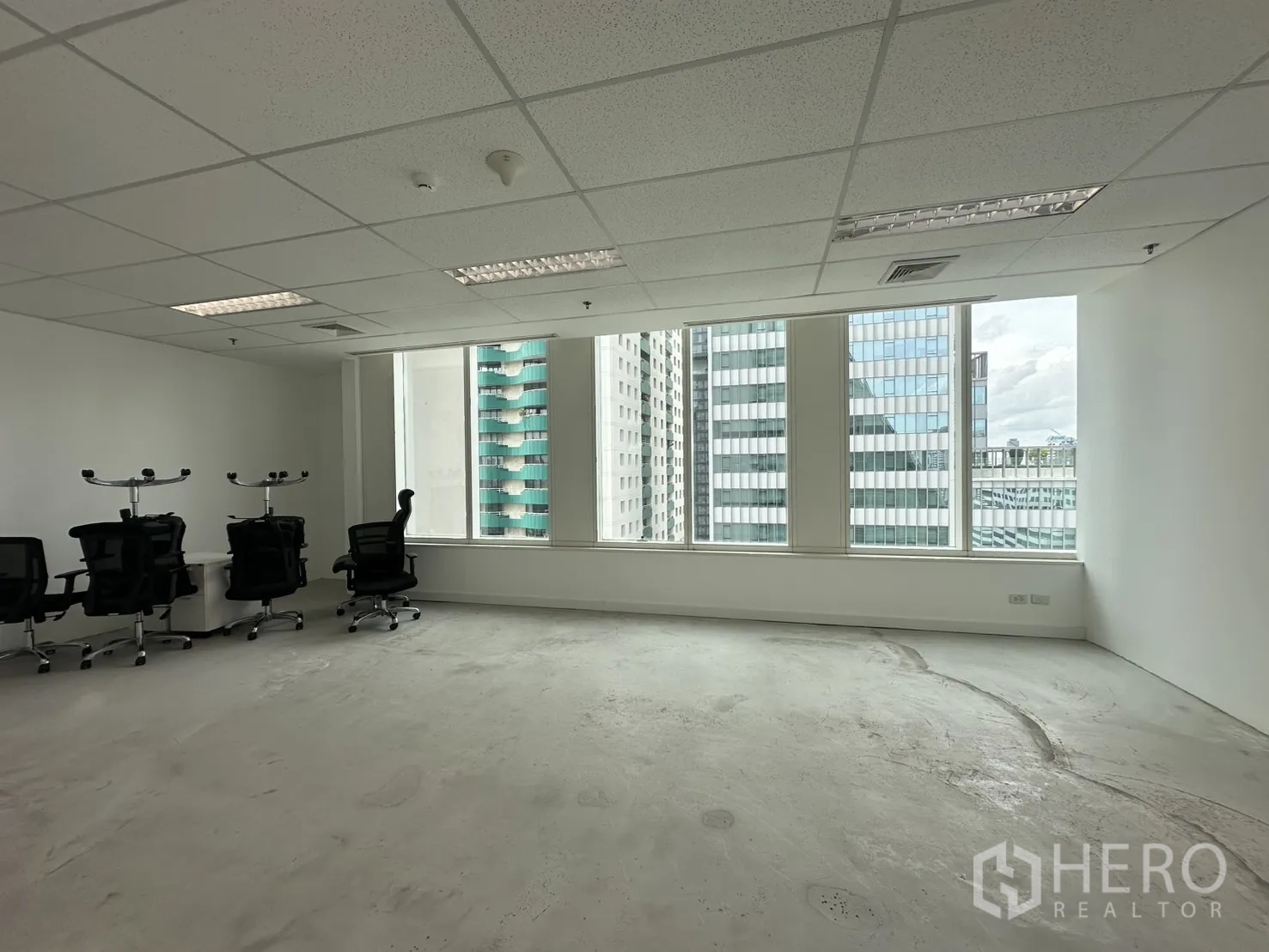 办公室 for rent in Watthana, Bangkok - 明亮的开放式办公室，大窗户与白色墙面，数把办公椅面向城市高楼景观。