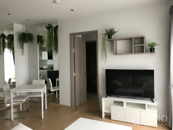公寓 出租在Watthana, Bangkok - 客厅配平板电视和壁架，旁接用餐区与开启的卧室门。