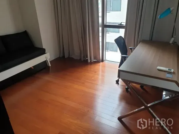 公寓 出租在Pathum Wan, Bangkok - 多功能房布置为书房，木地板，大书桌与高窗帘窗。