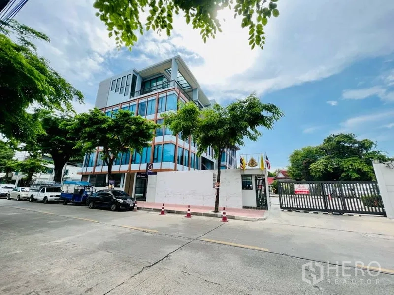 办公空间 出租在Khlong San, Bangkok - 街景一角：现代办公楼、行道树与大门入口。
