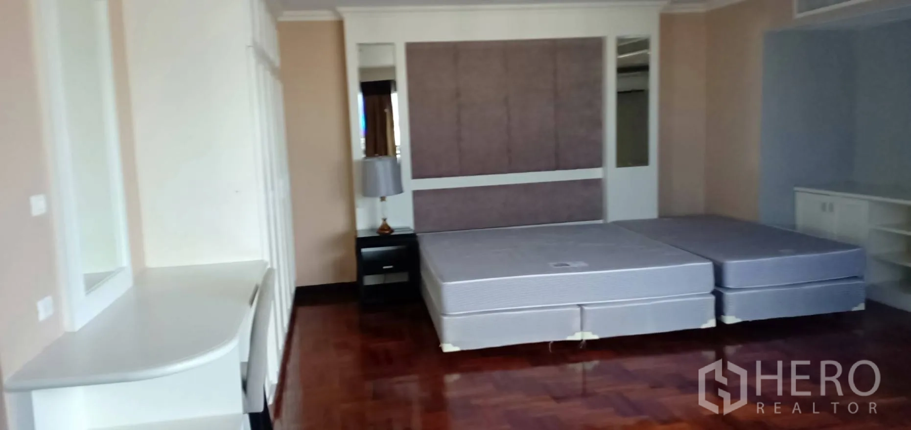 Condominium for rent in Watthana, Bangkok - Master bedroom angle with long work desk, wardrobes and glossy parquet flooring.