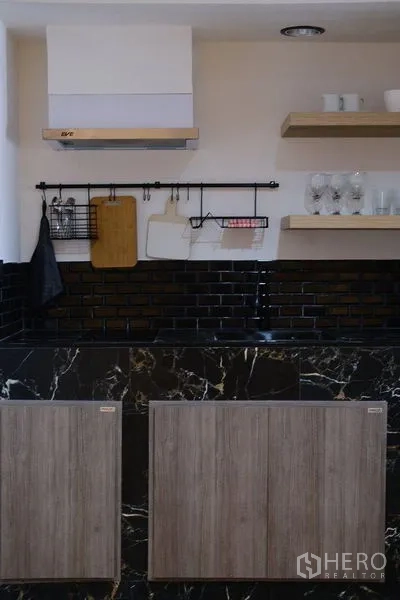 Condominium for rent in Bang Rak, Bangkok - Contemporary kitchen with open shelves and a black marble-look backsplash.
